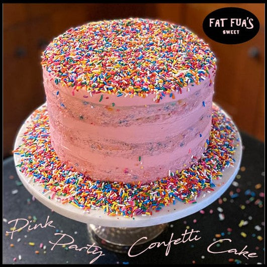 Pink naked confetti cakes made with moist vanilla cake and whipped cream cheese frosting sitting on marble cake stands exploding with rainbow colored sprinkles