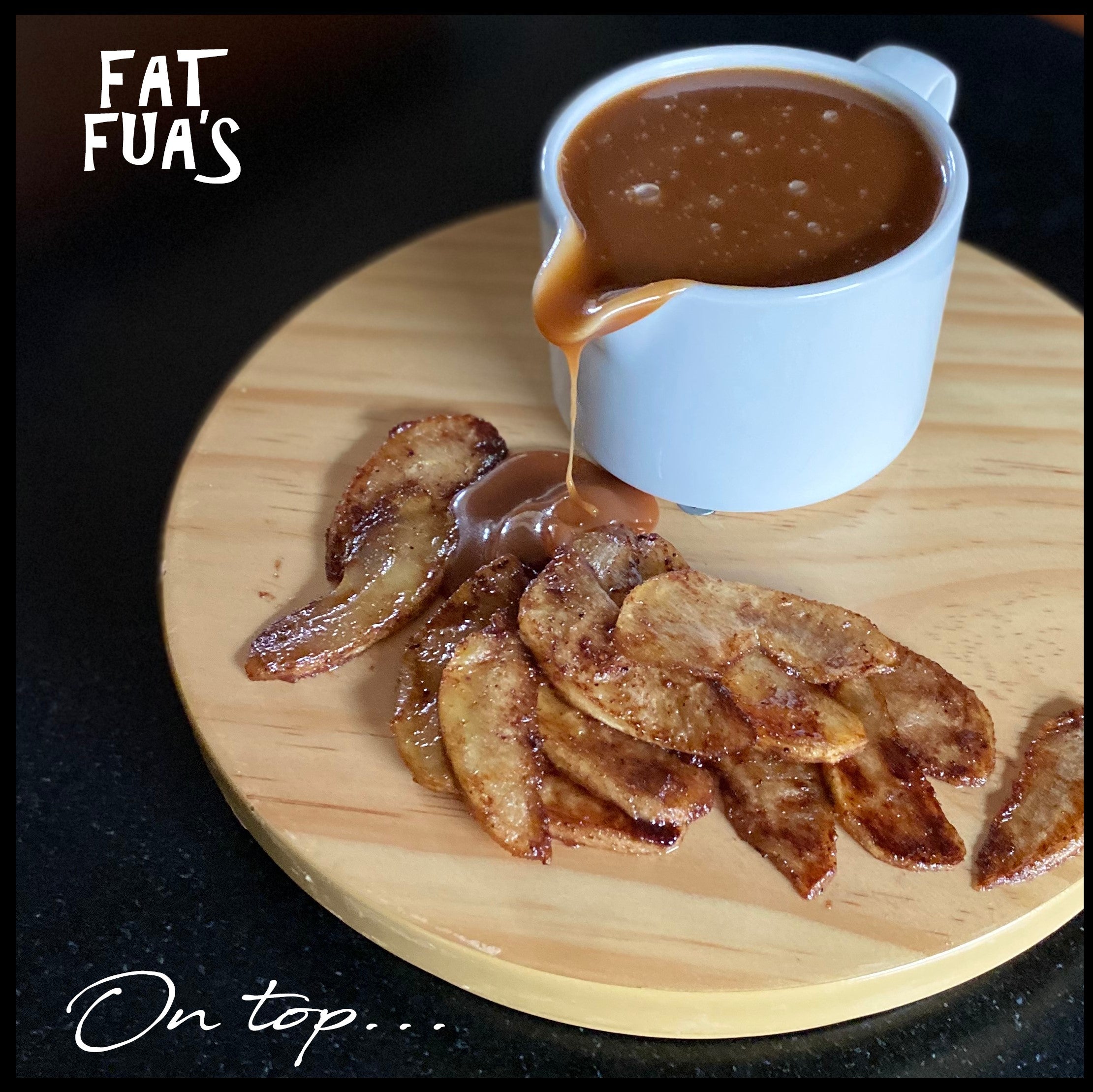 White porcelain bowl overflowing with salted caramel onto a pile of  apples pan fried in butter and brown sugar resting on a natural wooden tray