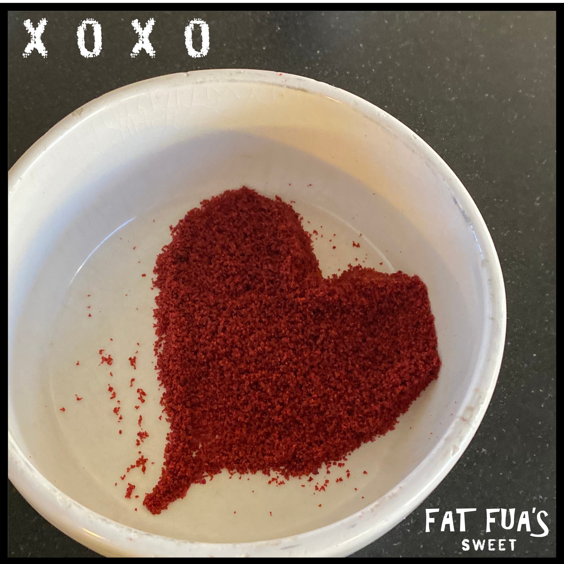 Photo of white ceramic bowl with red velvet dust sprinkled into a heart shape with the letters XOXO next to it