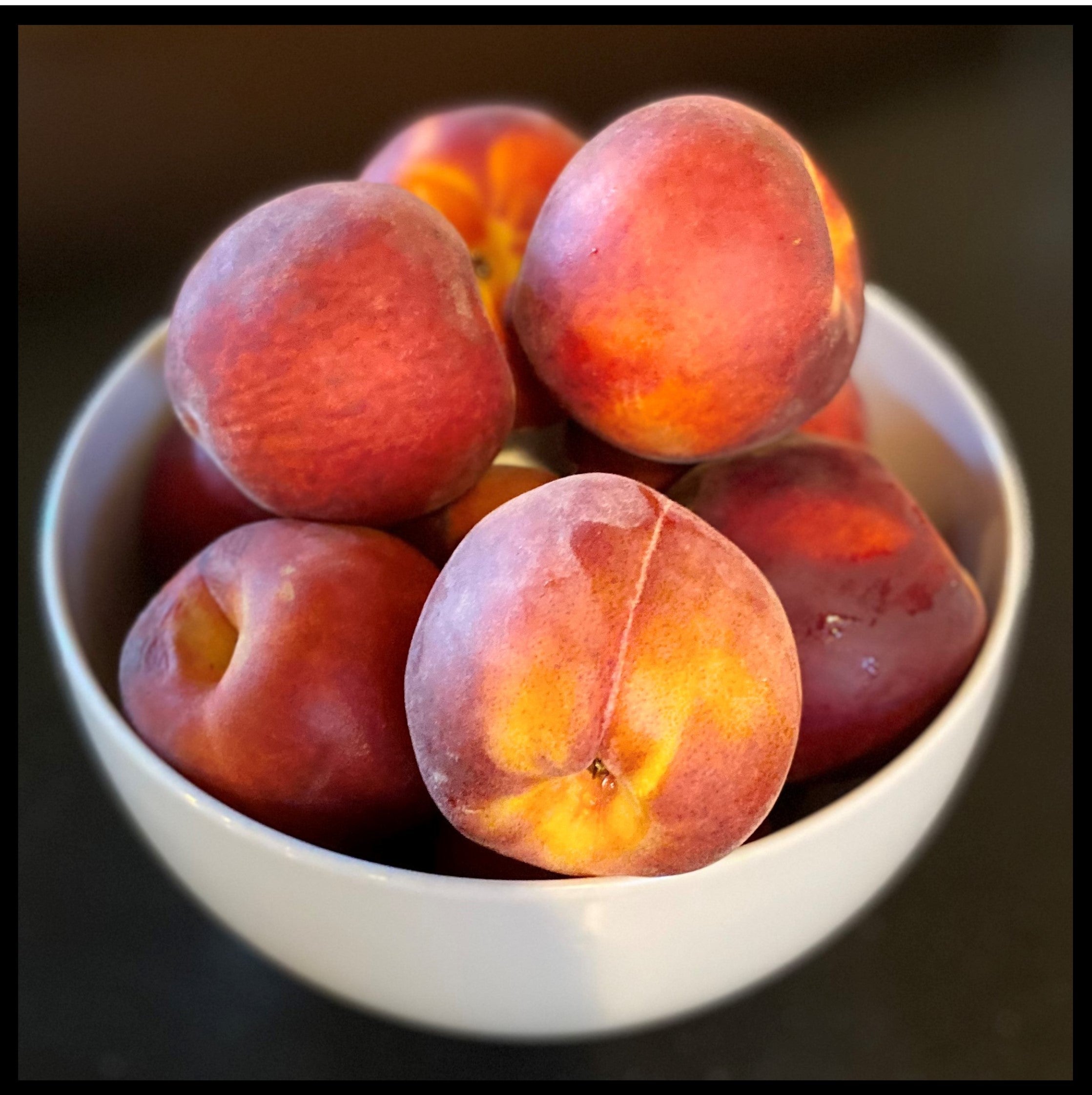 White bowl of fresh peaches