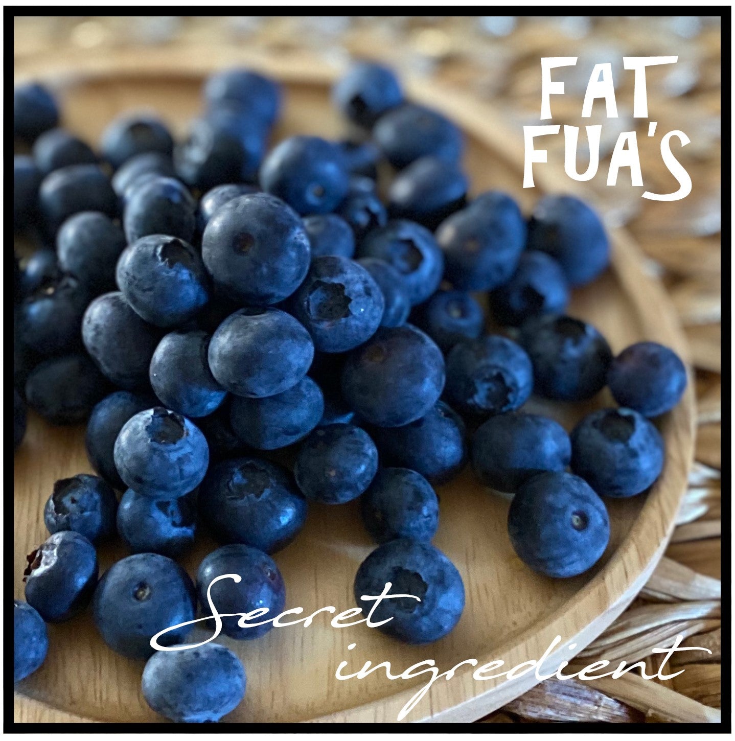 heaping pile of fresh blueberries laying on a bleached wood plate on a natural grass mat